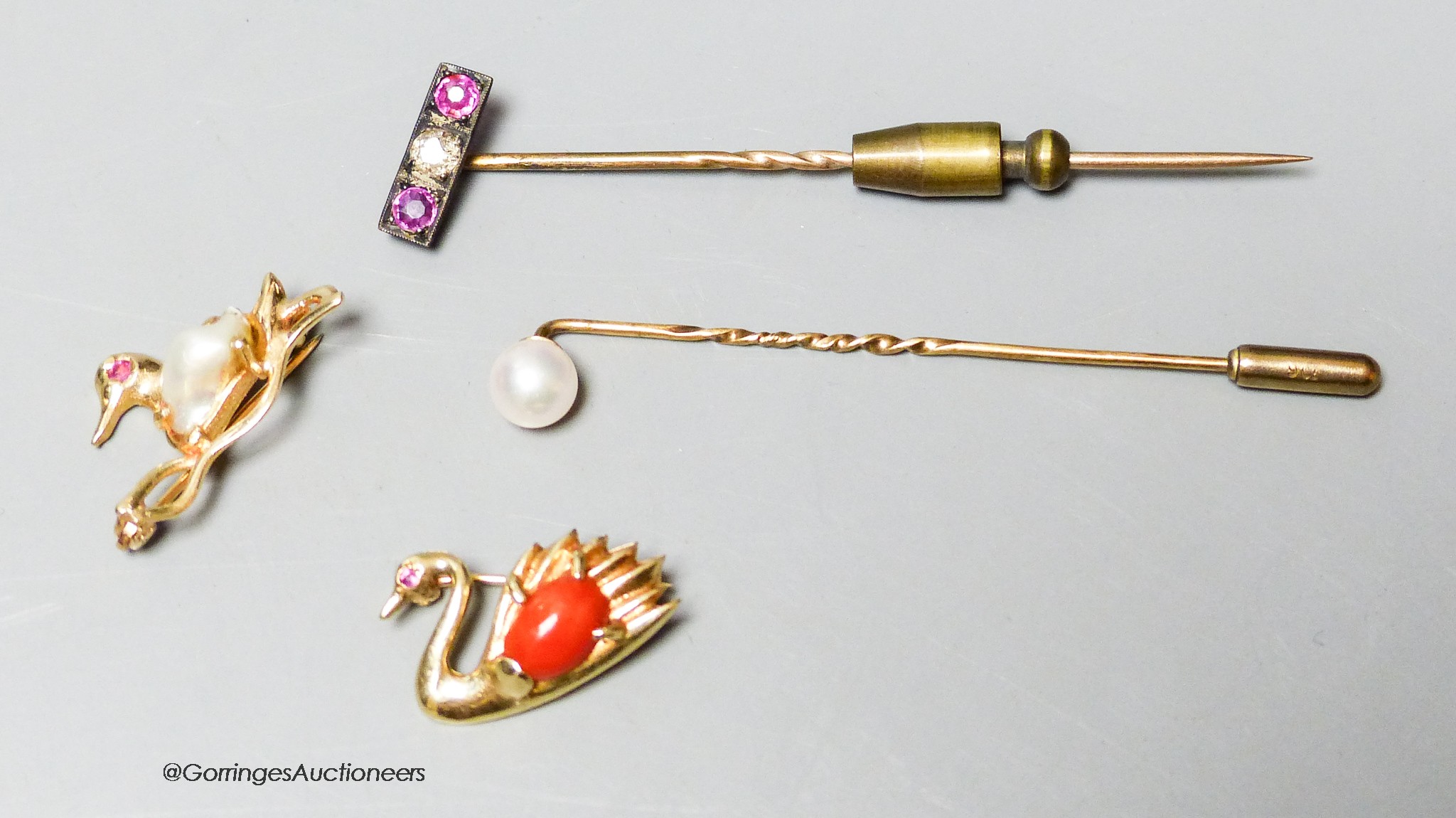 A modern 14k, baroque pearl and gem set duck brooch, 22mm and a similar coral set swan brooch, gross 4.7 grams and two stick pins including ruby & diamond three stone.